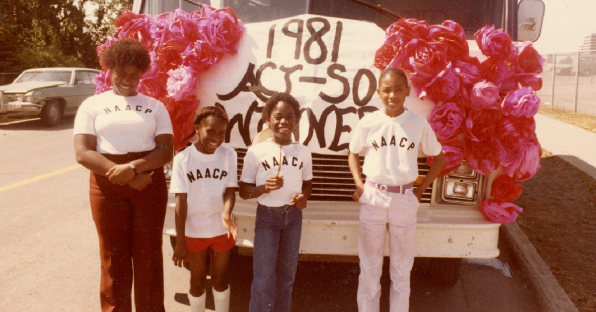 Young people in front of a sign for the NAACP Afro-Academic, Cultural, Technological and Scientific Olympics (ACT-SO) in Anchorage, 1981. 